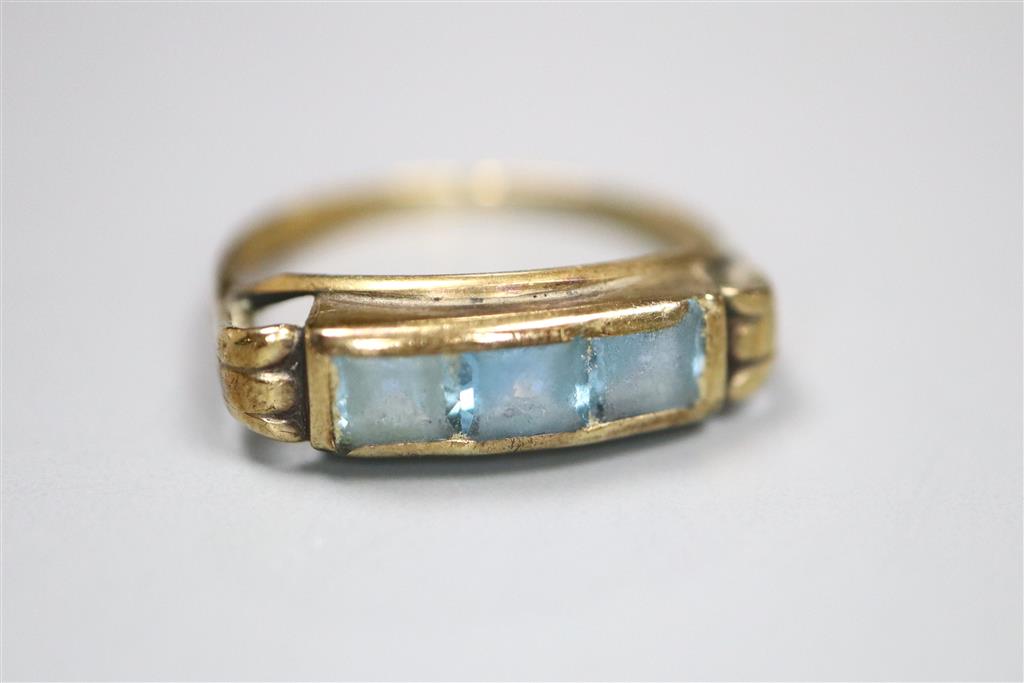 A 333 (8ct) yellow metal and channel set three stone blue topaz? ring, size J, gross 1.4 grams.